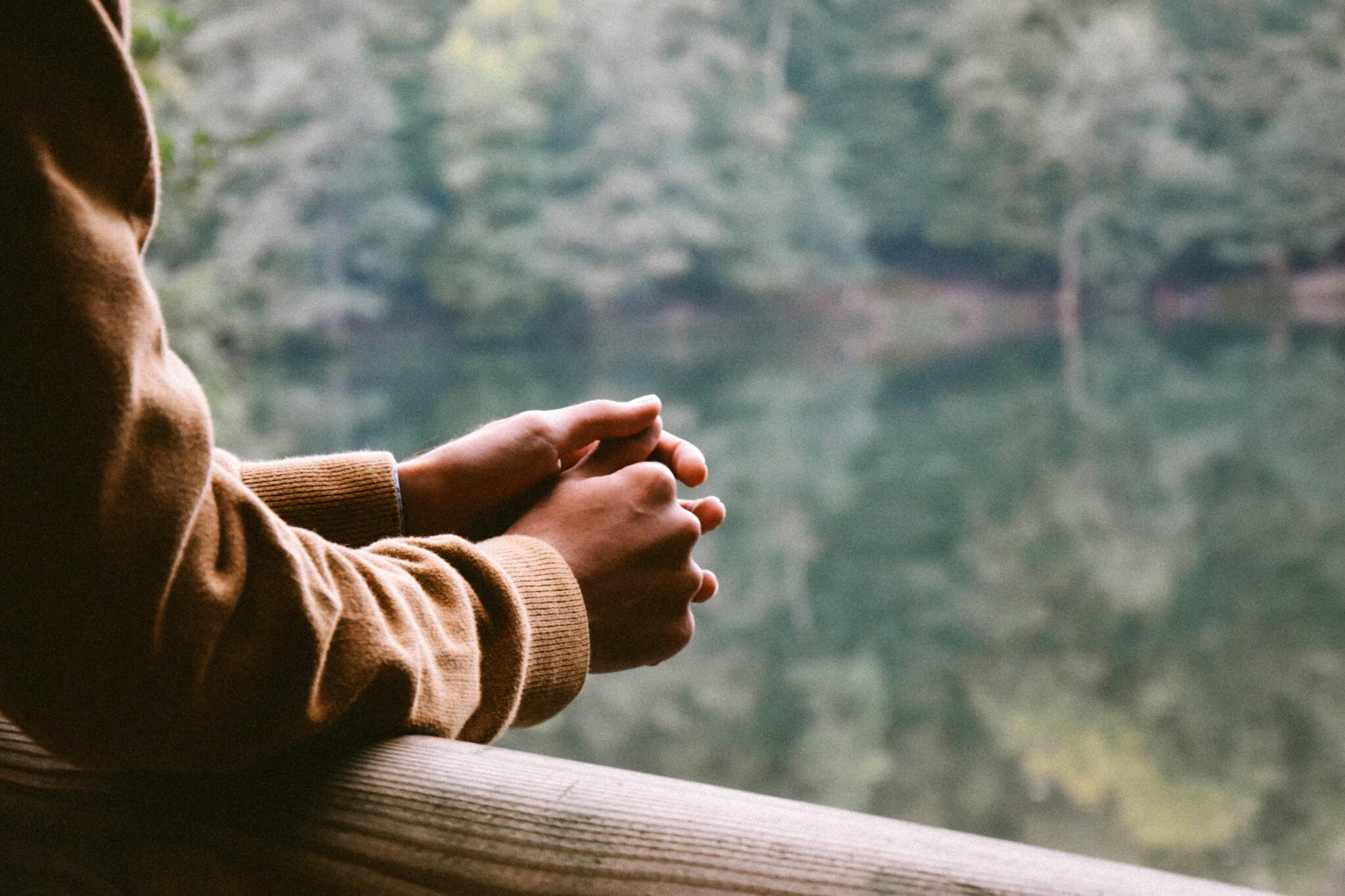 A person with their hands clasped together on the side of a bridge.